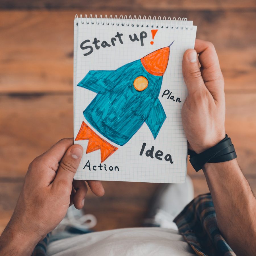 Your dreams may come true. Top view of man holding note pad with drawing on it while standing on the wooden floor